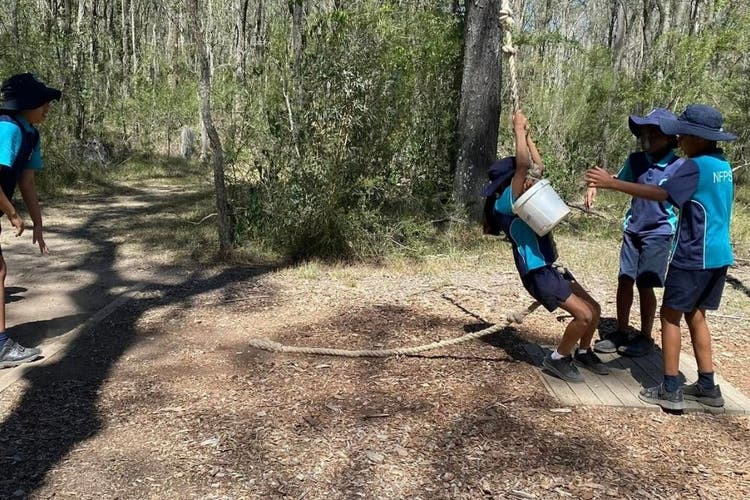A student swinging on a rope while completing a team challenge