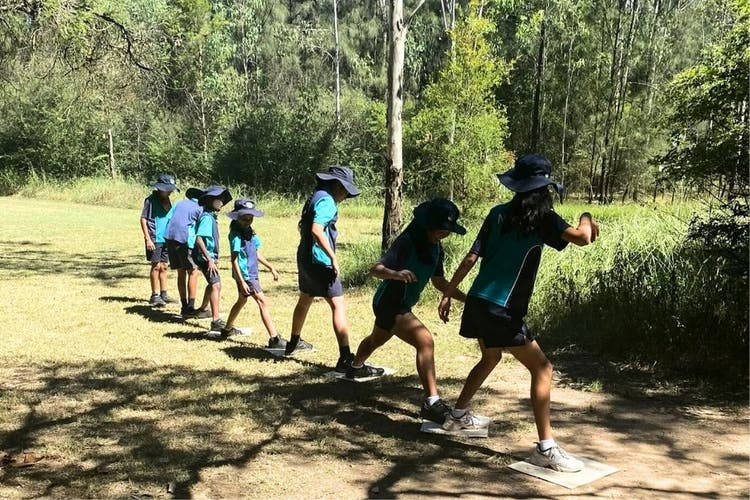 Students stepping across mats while completing a team challenge