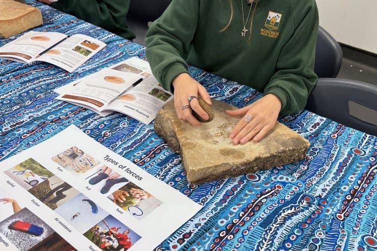 A sudent using a grinding stone during an incursion